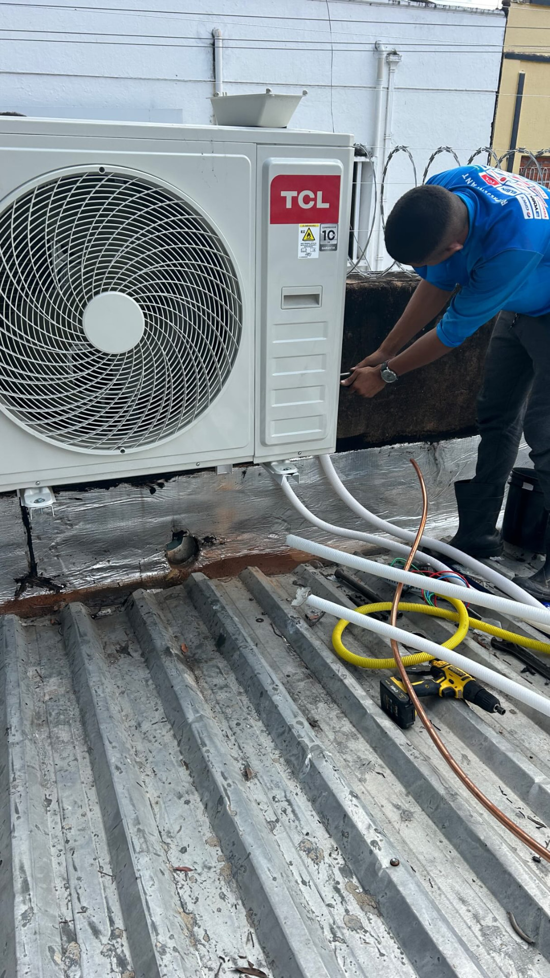 Técnico da DL Refrigeração instalando condensadora TCL em telhado